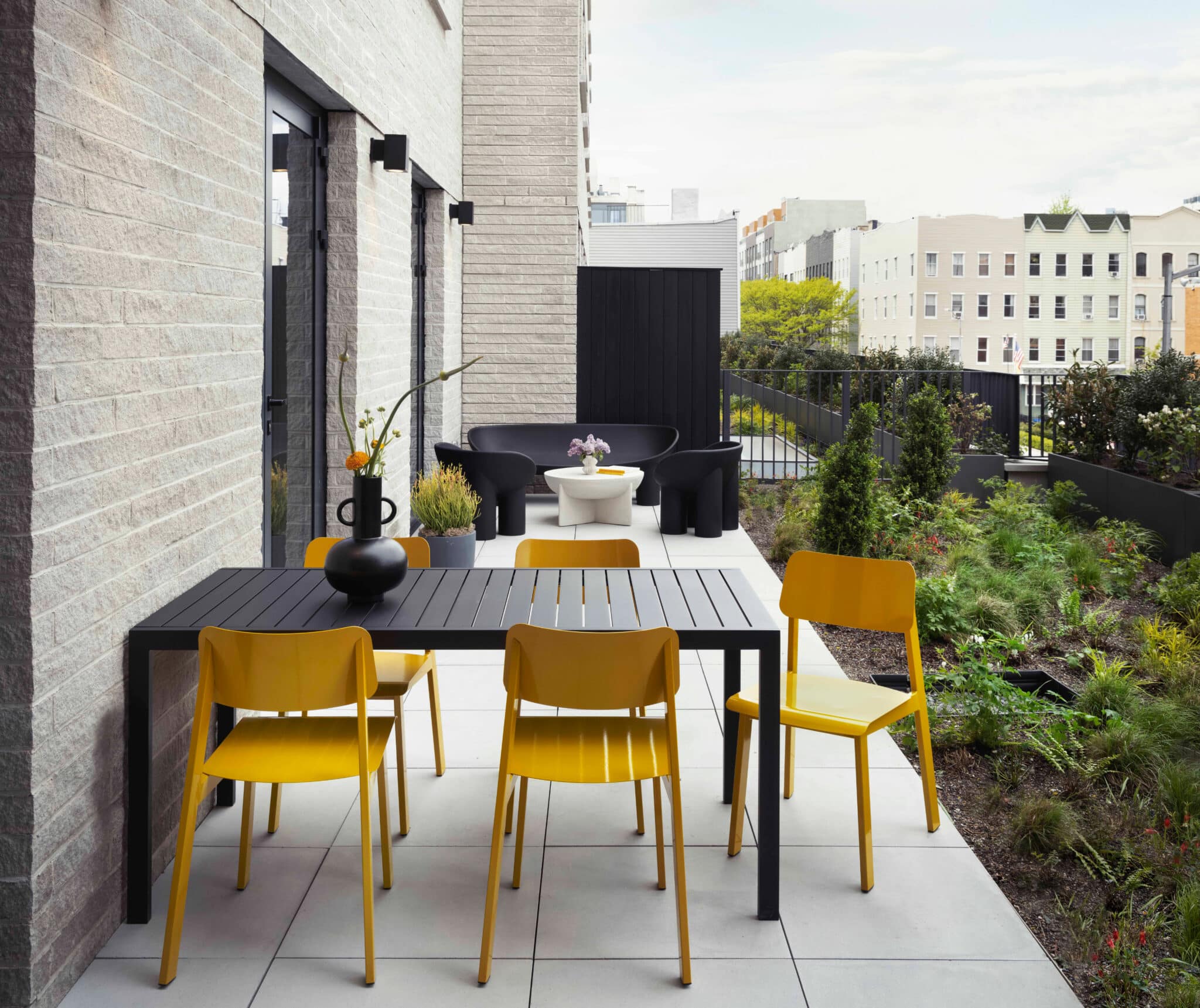 A small outdoor seating area with a black table and yellow chairs.