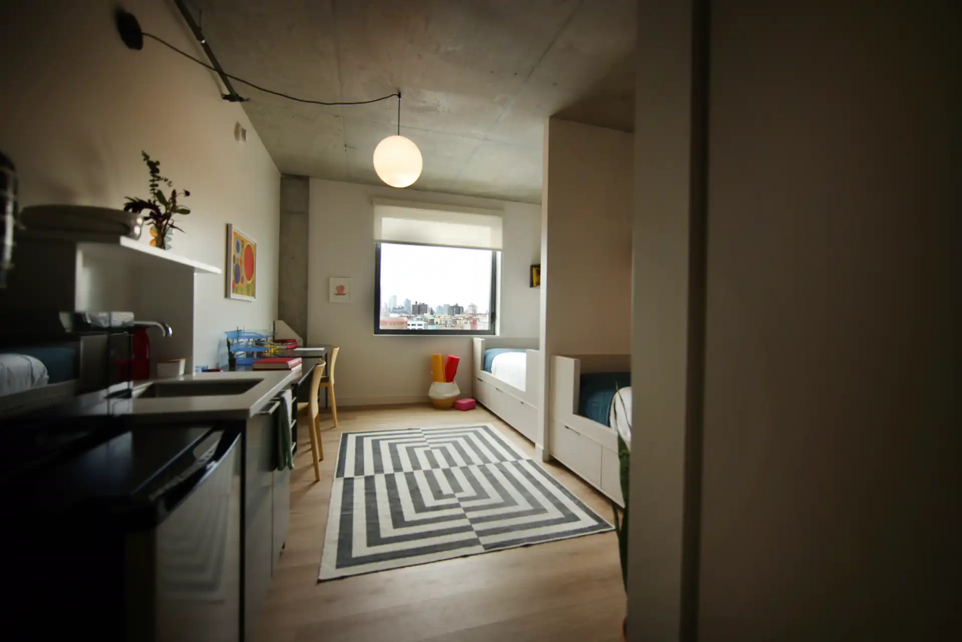 A compact room with a kitchenette, bed, and city view.