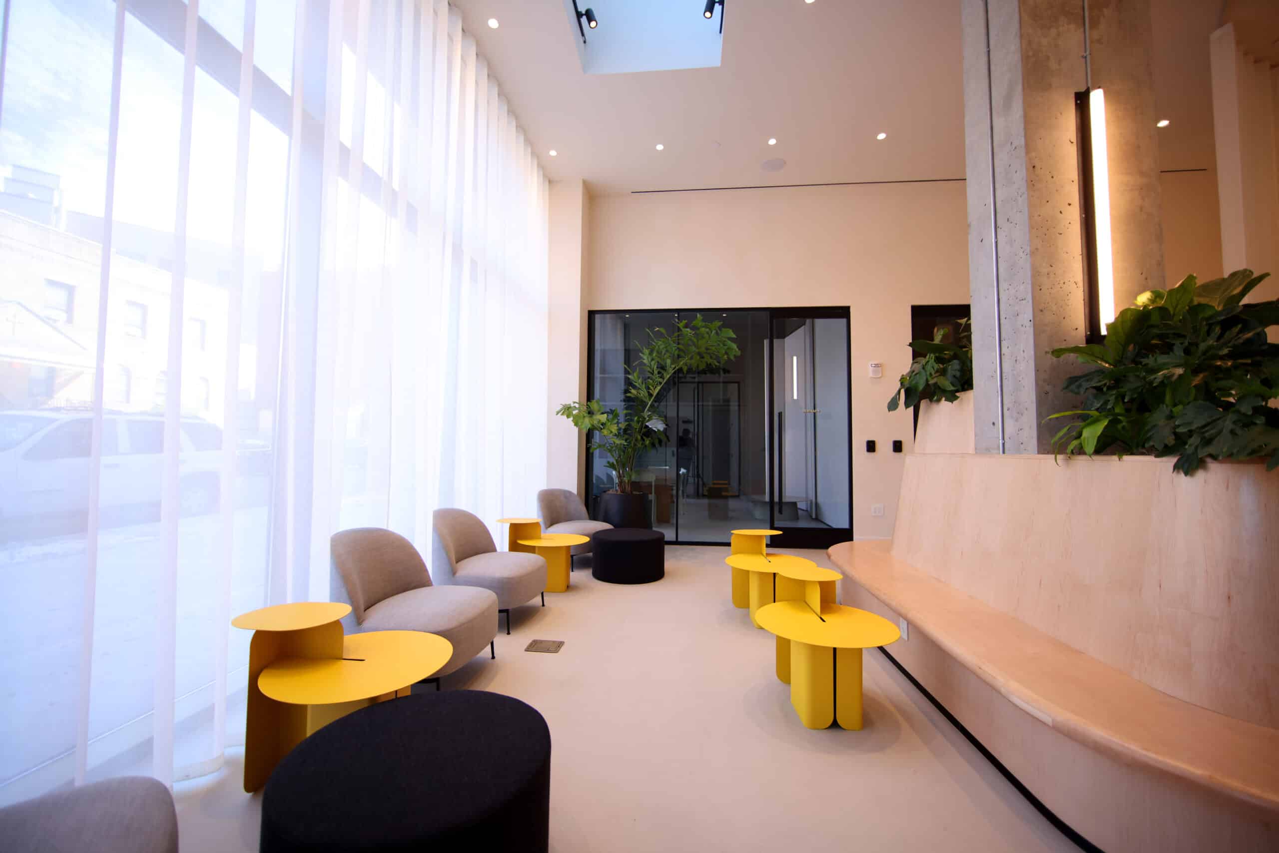 A modern lobby with a seating area, large windows, and plants.