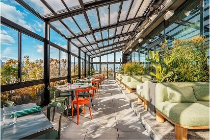 A dining area with a glass roof, green seating, and outdoor dining tables.